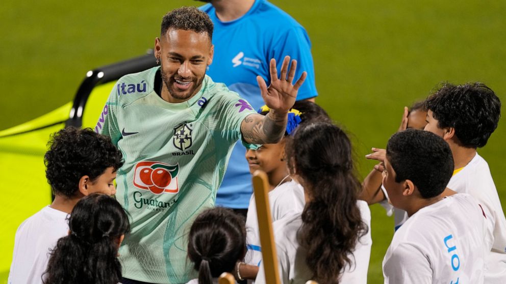 Brazil's Neymar greets children from a FIFA social project after a training session at the Grand Hamad stadium in Doha, Qatar, Sunday, Nov. 20, 2022. Brazil will play their first match in the World Cup against Serbia on Nov. 24. (AP Photo/Andre Penner)