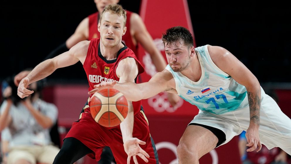 Germany's Niels Giffey (5), left, and Slovenia's Luka Doncic (77) fight for a loose ball during men's basketball quarterfinal game at the 2020 Summer Olympics, Tuesday, Aug. 3, 2021, in Saitama, Japan. (AP Photo/Charlie Neibergall)