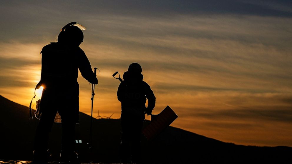FILE - Workers arrive at the sunrise before the women's slopestyle finals at the 2022 Winter Olympics, Sunday, Feb. 6, 2022, in Zhangjiakou, China. (AP Photo/Kiichiro Sato, File)