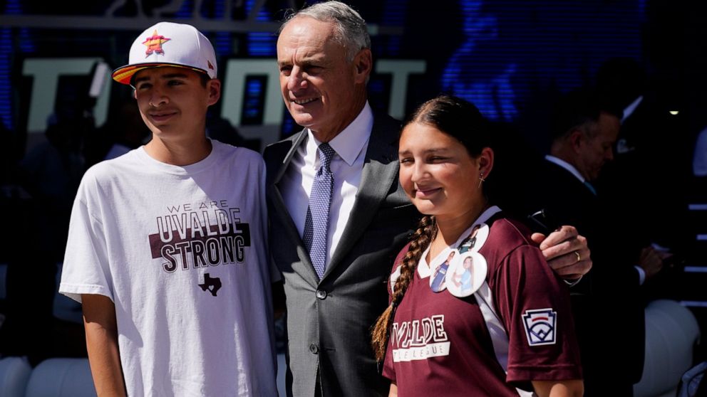 MLB Commissioner Rob Manfred, center, poses for photos with Aidan, left, and Willa Suarez, of Uvalde, Tex., during the 2022 MLB baseball draft, Sunday, July 17, 2022, in Los Angeles. (AP Photo/Jae C. Hong)