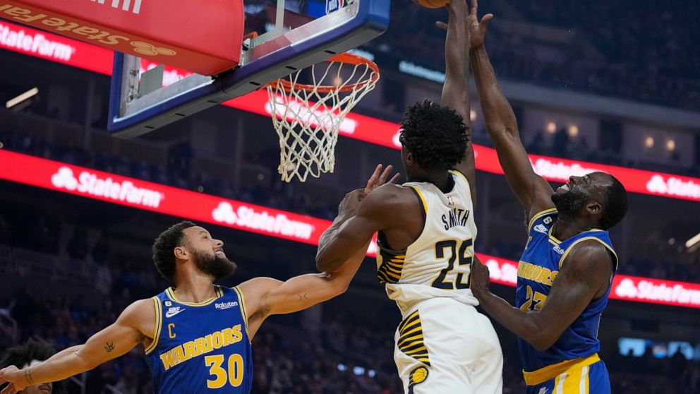 Indiana Pacers forward Jalen Smith (25) dunks against Golden State Warriors guard Stephen Curry (30) and forward Draymond Green during the first half of an NBA basketball game in San Francisco, Monday, Dec. 5, 2022. (AP Photo/Godofredo A. Vásquez)