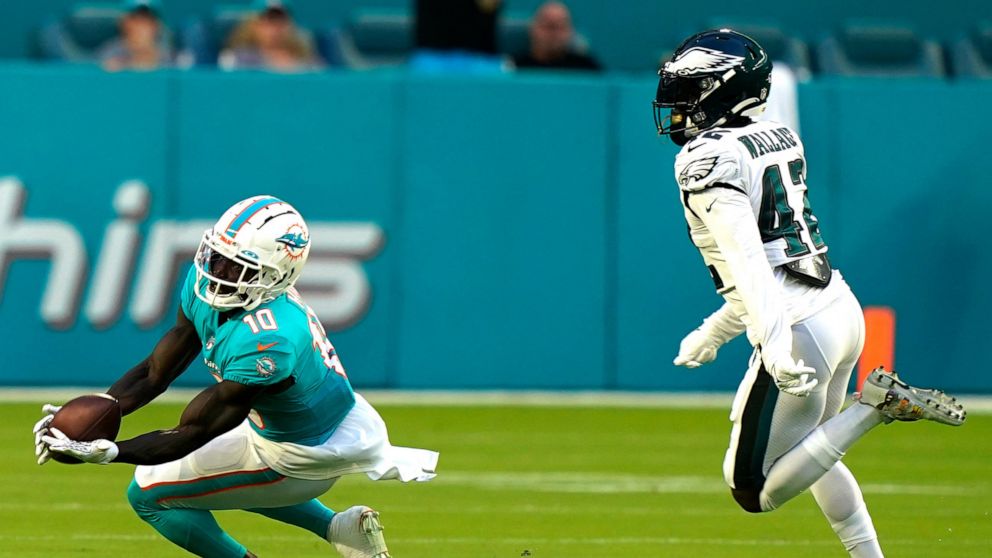 Miami Dolphins wide receiver Tyreek Hill (10) grabs a pass as Philadelphia Eagles safety K'Von Wallace (42) is late with the tag during the first half of a NFL preseason football game, Saturday, Aug. 27, 2022, in Miami Gardens, Fla. (AP Photo/Lynne S