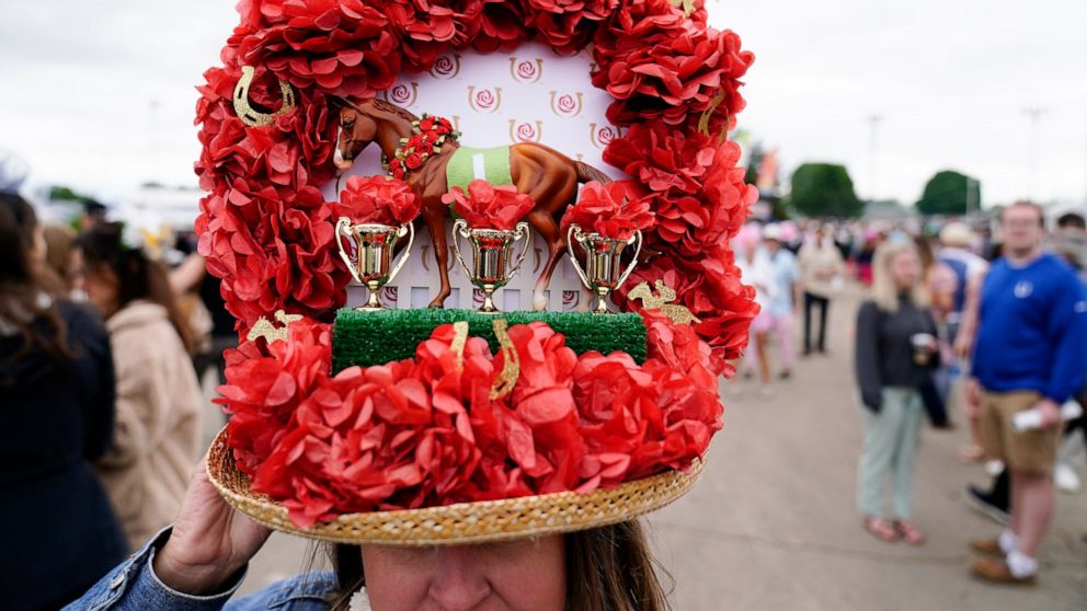 A woman wears a decorative hat as she walks through the infield before the 148th running of the Kentucky Derby horse race at Churchill Downs Saturday, May 7, 2022, in Louisville, Ky. (AP Photo/Brynn Anderson)
