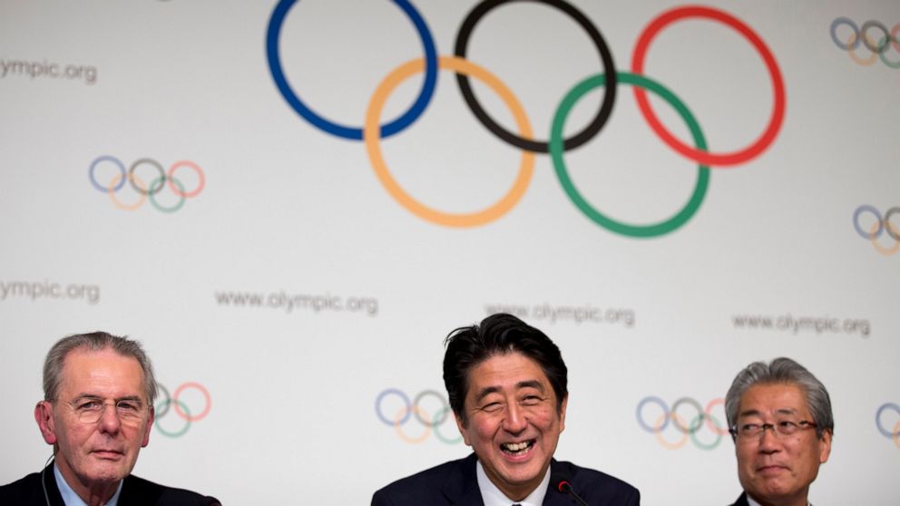 FILE - Then Japan's Prime Minister Shinzo Abe, center, smiles next to the President of the International Olympic Committee Jacques Rogge, left, as Tokyo 2020 Olympic Bid Committee President Tsunekazu Takeda, right, looks on after signing the Host Cit