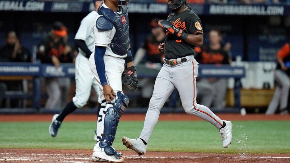 Baltimore Orioles' Jorge Mateo, right, scores in front of Tampa Bay Rays catcher Christian Bethancourt on a sacrifice fly by Adley Rutschman during the fifth inning of a baseball game Friday, Aug. 12, 2022, in St. Petersburg, Fla. (AP Photo/Chris O'Meara)
