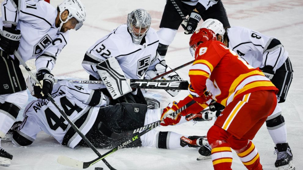 Los Angeles Kings goalie Jonathan Quick (32) looks on as forward Anze Kopitar, left, tries to clear the puck while Calgary Flames forward Elias Lindholm digs for it during third-period NHL hockey game action in Calgary, Alberta, Monday, Nov. 14, 2022