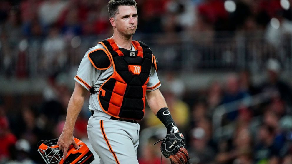 FILE - San Francisco Giants catcher Buster Posey walks on the field during the team's baseball game against the Atlanta Braves on Aug. 27, 2021, in Atlanta. The Giants announced Wednesday, Sept. 21, 2022, that the 35-year-old former catcher has joine