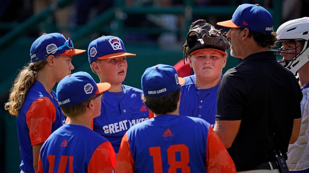 Hagerstown, Ind. manager Patrick Vinson, right, talks with his team on the mound during the second inning of a baseball game against Hollidaysburg, Pa., at the Little League World Series in South Williamsport, Pa., Tuesday, Aug. 23, 2022. (AP Photo/G