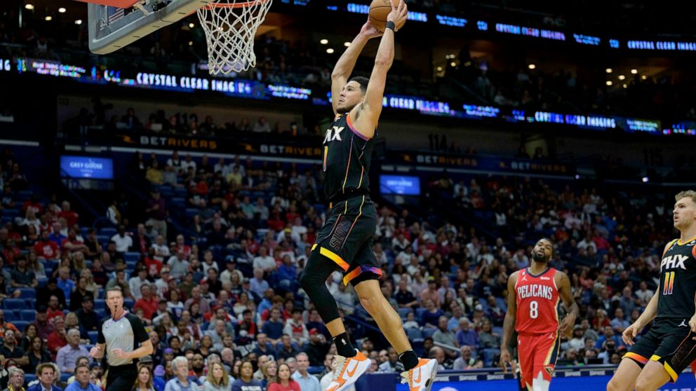 Phoenix Suns guard Devin Booker (1) goes up to dunk against the New Orleans Pelicans in the first half of an NBA basketball game in New Orleans, Friday, Dec. 9, 2022. (AP Photo/Matthew Hinton)