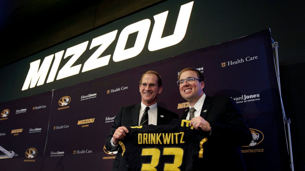 University of Missouri Director of Athletics Jim Sterk, left, holds up a jersey with Eliah Drinkwitz after introducing Drinkwitz as the new NCAA college football head coach at the school, Tuesday, Dec. 10, 2019, in Columbia, Mo. Drinkwitz becomes the
