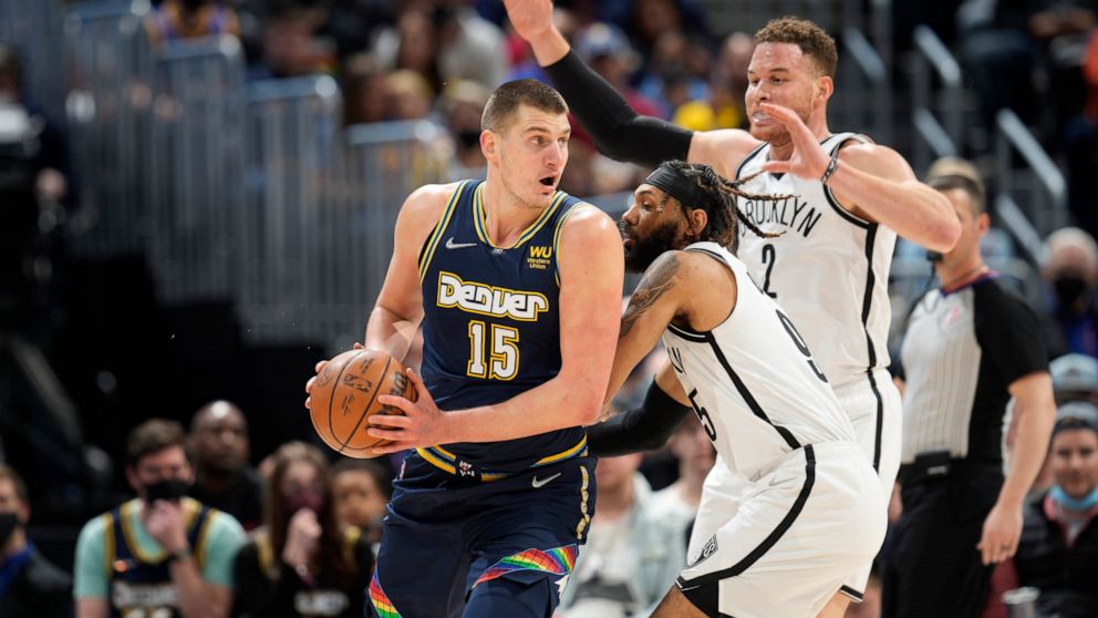 Denver Nuggets center Nikola Jokic, left, looks to pass the ball as Brooklyn Nets guard DeAndre' Bembry, center, and forward Blake Griffin defend in the first half of an NBA basketball game Sunday, Feb. 6, 2022, in Denver. (AP Photo/David Zalubowski)