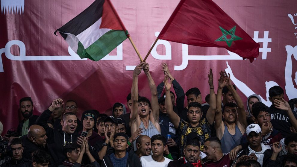 FILE - Palestinians wave Moroccan and their national flags as they watch a live broadcast of the World Cup quarterfinal soccer match between Morocco and Portugal played in Qatar, in Gaza City Saturday, Dec. 10, 2022. It's a rare moment in the Middle 