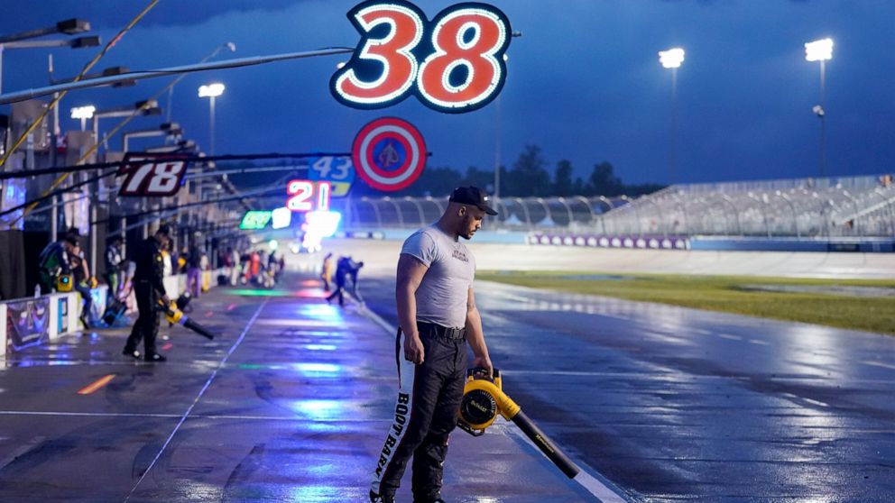 Jourdan Osinskie, the jack man on the pit crew for driver Todd Gilliland, tries to dry off their pit box during a storm delay at a NASCAR Cup Series auto race Sunday, June 26, 2022, in Lebanon, Tenn. (AP Photo/Mark Humphrey)