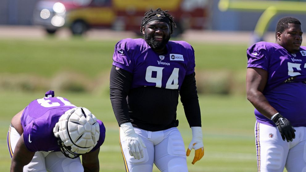Minnesota Vikings defensive tackle Dalvin Tomlinson (94) jokes with teammates at the NFL football team's practice facility in Eagan, Minn., Friday, Aug. 5, 2022. (AP Photo/Stacy Bengs)
