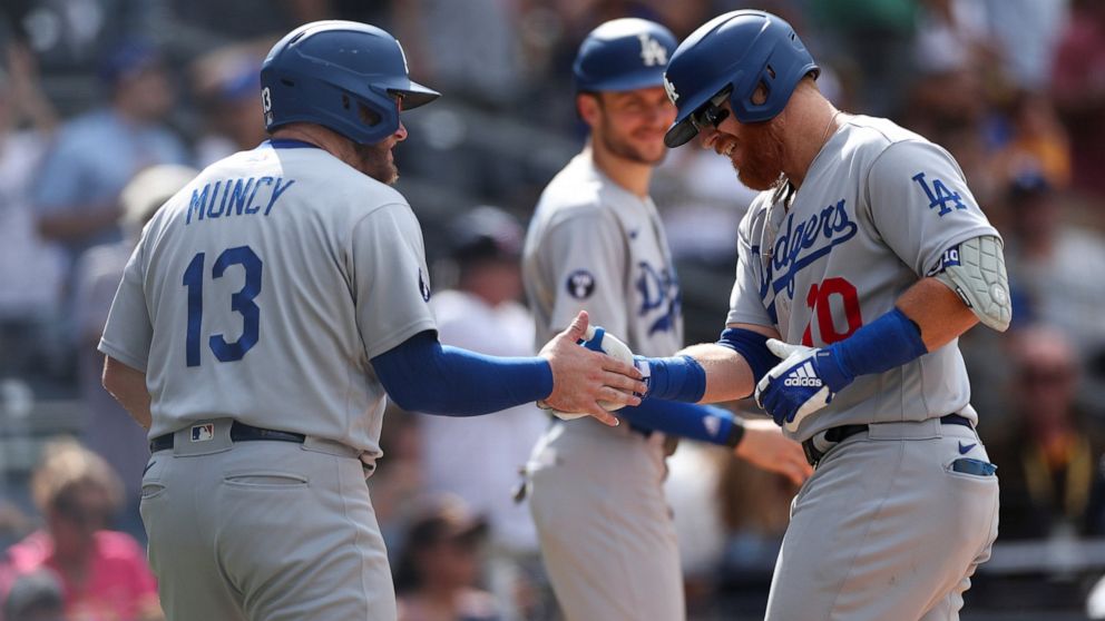 Los Angeles Dodgers' Justin Turner, right, is congratulated by Max Muncy after hitting a grand slam against the San Diego Padres in the seventh inning of a baseball game Sunday, Sept. 11, 2022, in San Diego. (AP Photo/Derrick Tuskan)