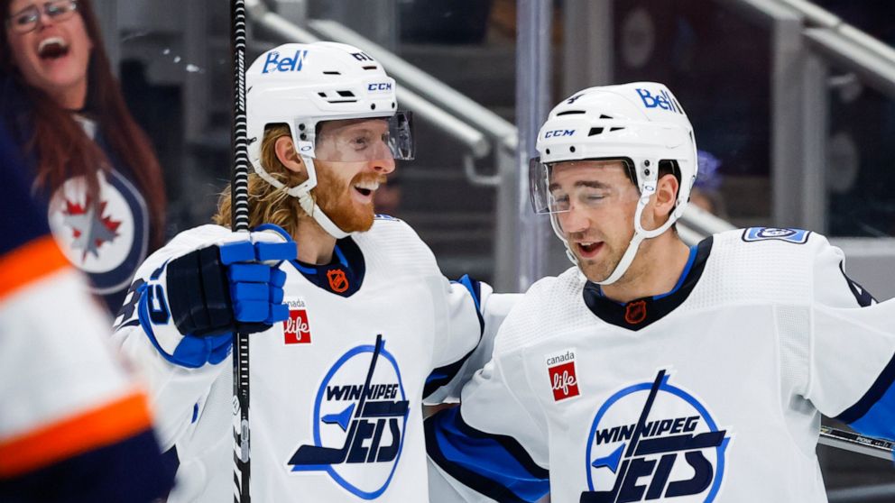 Winnipeg Jets forward Kyle Connor, left, celebrates his goal against the Edmonton Oilers with Neal Pionk during the third period of an NHL hockey game Saturday, Dec. 31, 2022, in Edmonton, Alberta. (Jeff McIntosh/The Canadian Press via AP)
