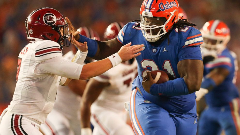 Florida defensive lineman Desmond Watson (21) stiff arms South Carolina quarterback Spencer Rattler (7) after recovering a fumble during the second half of an NCAA college football game, Saturday, Nov. 12, 2022, in Gainesville, Fla. (AP Photo/Matt Stamey)