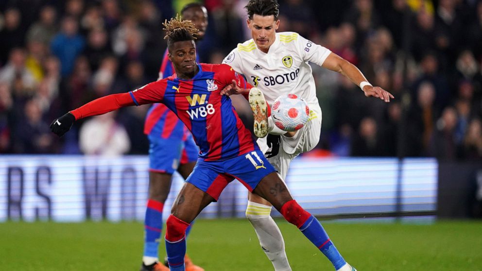 Crystal Palace's Wilfried Zaha, left, and Leeds United's Robin Koch battle for the ball during the English Premier League soccer match between Crystal Palace and Leeds United at Selhurst Park, London, Monday April 25, 2022. (John Walton/PA via AP)