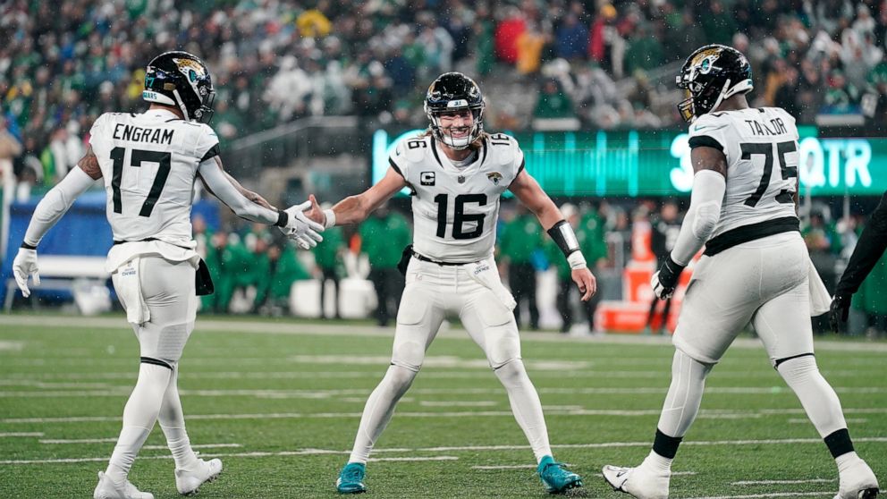 Jacksonville Jaguars quarterback Trevor Lawrence (16) celebrates with tight end Evan Engram (17) and offensive tackle Jawaan Taylor (75) after scoring a touchdown against the New York Jets during the second quarter of an NFL football game, Thursday, 