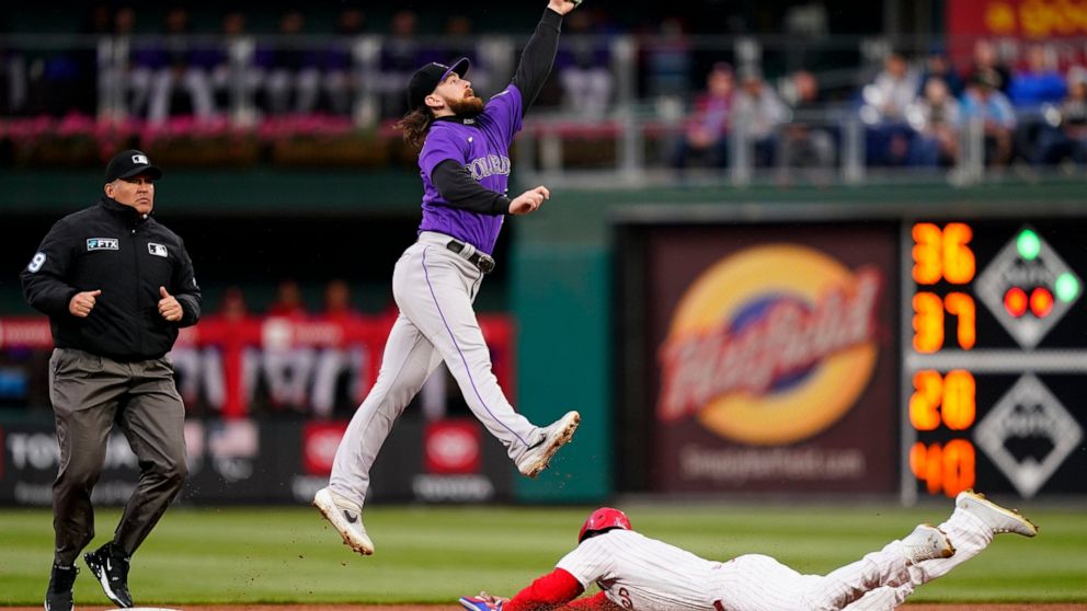 Philadelphia Phillies' Bryce Harper, right, steals second under Colorado Rockies second baseman Brendan Rodgers during the first inning of a baseball game, Tuesday, April 26, 2022, in Philadelphia. (AP Photo/Matt Slocum)