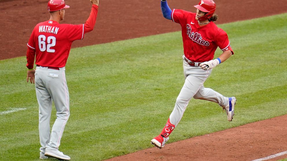 Philadelphia Phillies' Alec Bohm, right, rounds third to greetings from third base coach Dusty Wathan after hitting a solo home run off Pittsburgh Pirates relief pitcher Dillon Peters during the sixth inning of a baseball game in Pittsburgh, Sunday, 