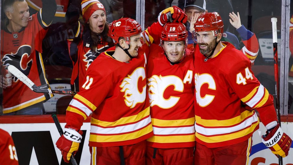 Calgary Flames' Matthew Tkachuk, center, is congratulated by Mikael Backlund, left, and Erik Gudbranson after Tkachuk scored against the Vegas Golden Knights during the third period of an NHL hockey game Thursday, Feb. 9, 2022, in Calgary, Alberta. (