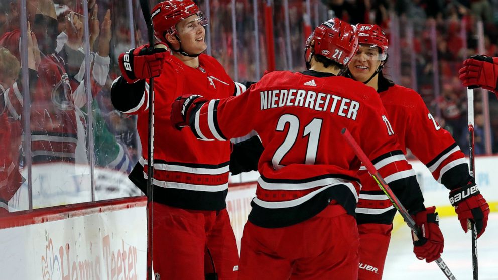 Carolina Hurricanes' Martin Necas, left, celebrates his goal with teammates Nino Niederreiter (21) and Ethan Bear (25) during the second period of an NHL hockey game against the Tampa Bay Lightning in Raleigh, N.C., Tuesday, March 22, 2022. (AP Photo