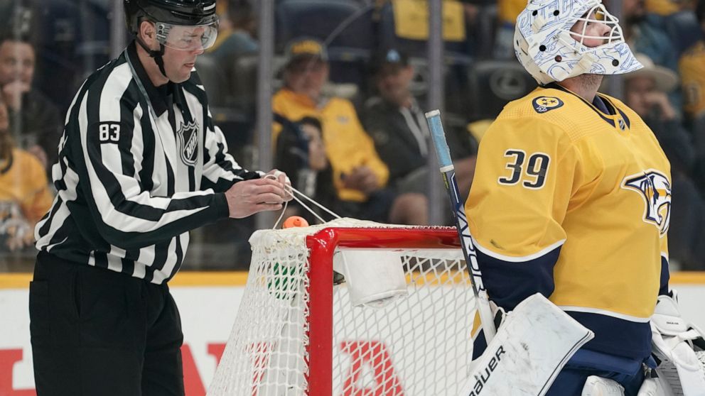 Linesman Matt MacPherson (83) repairs a hole in the net after a goal by the Colorado Avalanche broke the strings during the first period in Game 4 of an NHL hockey first-round playoff series against the Nashville Predators Monday, May 9, 2022, in Nas