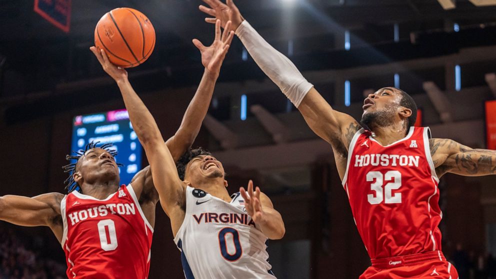 Virginia guard Kihei Clark, center, is blocked by Houston guard Marcus Sasser, left, and forward Reggie Chaney (32) during the second half of an NCAA college basketball game in Charlottesville, Va., Saturday, Dec. 17, 2022. (AP Photo/Erin Edgerton)