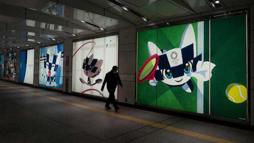 A man walks past large displays promoting the Tokyo 2020 Olympics in Tokyo, Tuesday, March 24, 2020. IOC President Thomas Bach has agreed "100%" to a proposal of postponing the Tokyo Olympics for about one year until 2021 because of the coronavirus o
