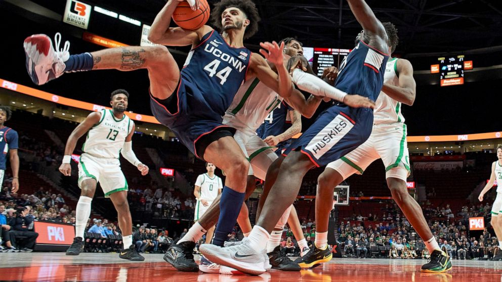 Connecticut forward Alex Karaban (44) collects a rebound ahead of Oregon guard Rivaldo Soares, center, during the first half of an NCAA college basketball game in the Phil Knight Invitational tournament in Portland, Ore., Thursday, Nov. 24, 2022. (AP