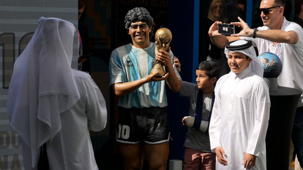 Children pose for a picture with a statue of the late soccer star Diego Maradona during a commemoration in his honor in Doha, in Friday, Nov. 25, 2022. (AP Photo/Jorge Saenz)