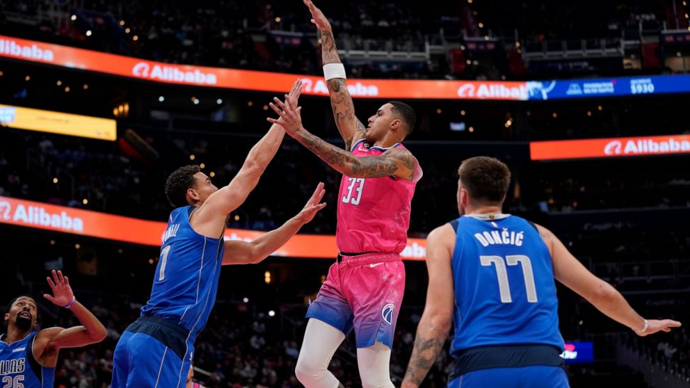 Washington Wizards forward Kyle Kuzma (33) shoots over Dallas Mavericks guard Spencer Dinwiddie, from left, center Dwight Powell and guard Luka Doncic, of Slovenia, in the first half of an NBA basketball game, Thursday, Nov. 10, 2022, in Washington. 