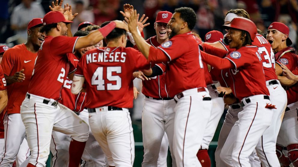 Teammates greet Washington Nationals' Joey Meneses (45) at home plate after he hit a three-run home run in the 10th inning of a baseball game against the Oakland Athletics, Thursday, Sept. 1, 2022, in Washington. Washington won 7-5. (AP Photo/Patrick