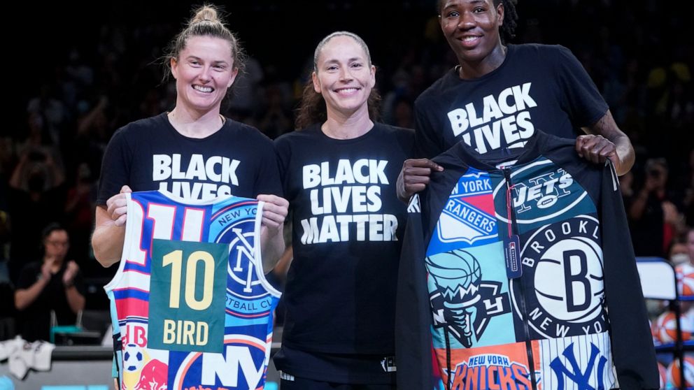 Seattle Storm guard Sue Bird, center, poses for a photo with former Storm teammates, New York Liberty forward Natasha Howard, left, and guard Sami Whitcomb during a presentation before a WNBA basketball game between the Liberty and the Storm, Sunday,