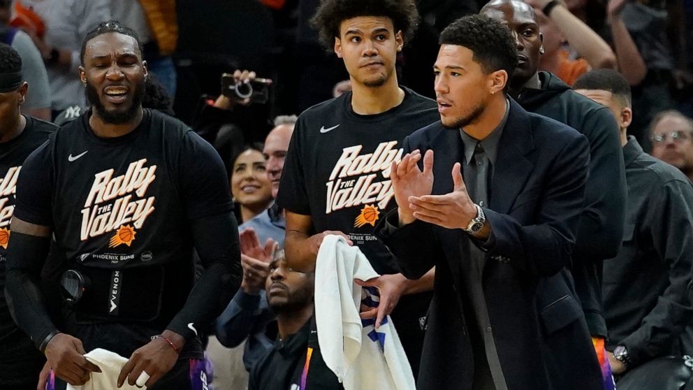 Phoenix Suns guard Devin Booker watches from the bench during the first half of Game 5 of an NBA basketball first-round playoff series against the New Orleans Pelicans, Tuesday, April 26, 2022, in Phoenix. (AP Photo/Matt York)