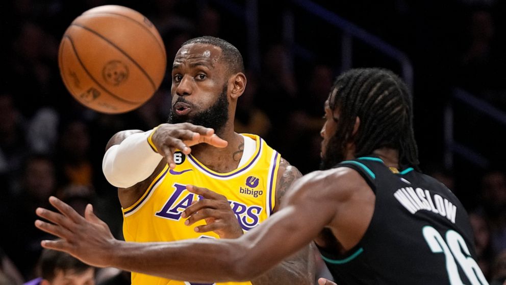 Los Angeles Lakers forward LeBron James, left, passes the ball as Portland Trail Blazers forward Justise Winslow defends during the first half of an NBA basketball game Wednesday, Nov. 30, 2022, in Los Angeles. (AP Photo/Mark J. Terrill)