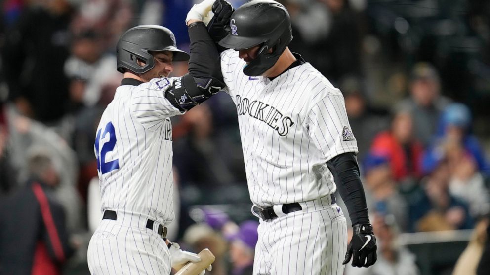 Colorado Rockies' Ryan McMahon, left, congratulates C.J. Cron on a solo home run off Chicago Cubs relief pitcher Chris Martin during the fifth inning of a baseball game Friday, April 15, 2022, in Denver. (AP Photo/David Zalubowski)