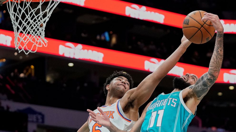 New York Knicks guard Quentin Grimes (6) attempts to block the shot of Charlotte Hornets forward Cody Martin (11) during the first half of an NBA basketball game Wednesday, March 23, 2022, in Charlotte, N.C. (AP Photo/Rusty Jones)