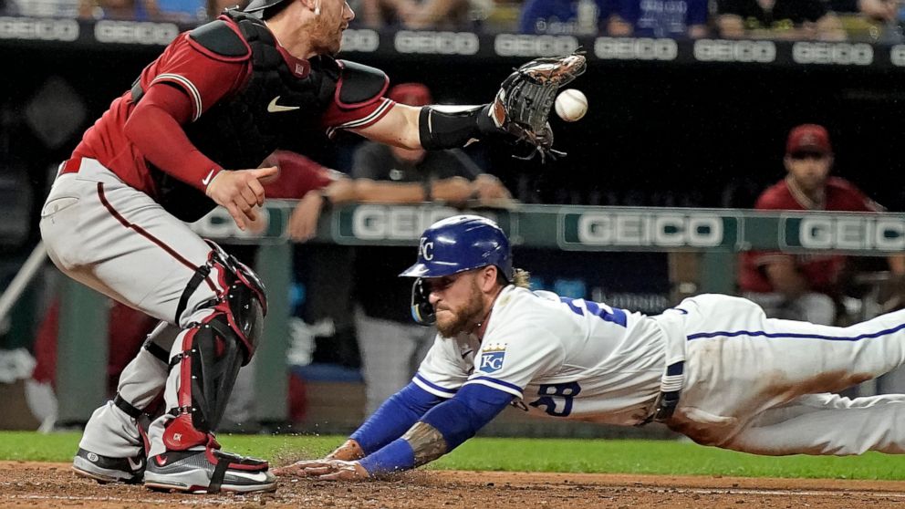 Kansas City Royals' Kyle Isbel beats the tag by Arizona Diamondbacks catcher Carson Kelly to score on a sacrifice bunt hit by Nicky Lopez during the seventh inning of a baseball game Wednesday, Aug. 24, 2022, in Kansas City, Mo. (AP Photo/Charlie Riedel)