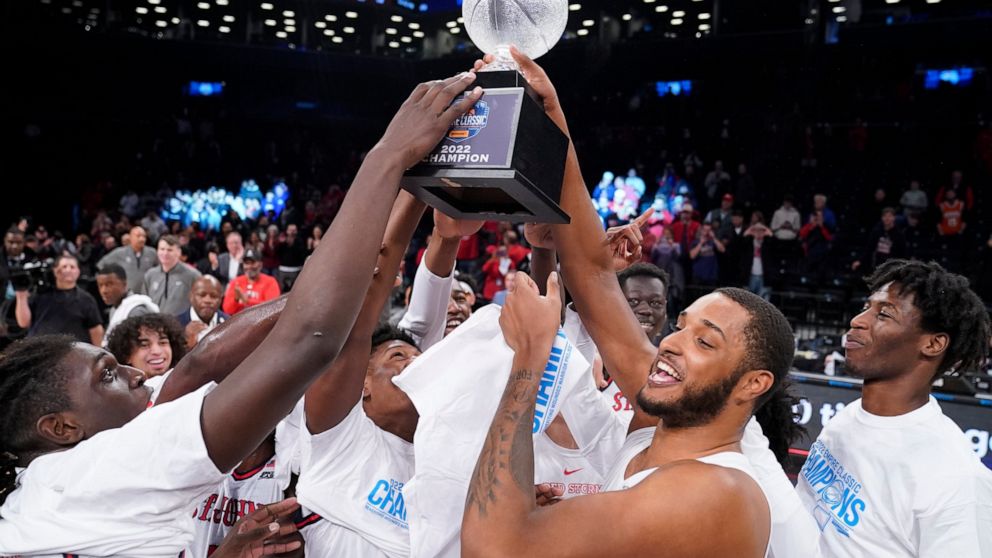St. John's Joel Soriano, center right, raises the championship trophy as he celebrates with his teammates after winning an NCAA college basketball championship game against Syracuse at the Good Samaritan Empire Classic, Tuesday, Nov. 22, 2022, in New