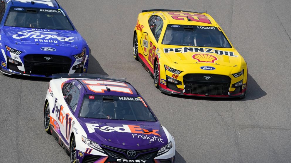 Joey Logano (22) races alongside Denny Hamlin (11) and Aric Almirola (10) during a NASCAR Cup Series auto race at World Wide Technology Raceway, Sunday, June 5, 2022, in Madison, Ill. Logano ended up winning the race. (AP Photo/Jeff Roberson)