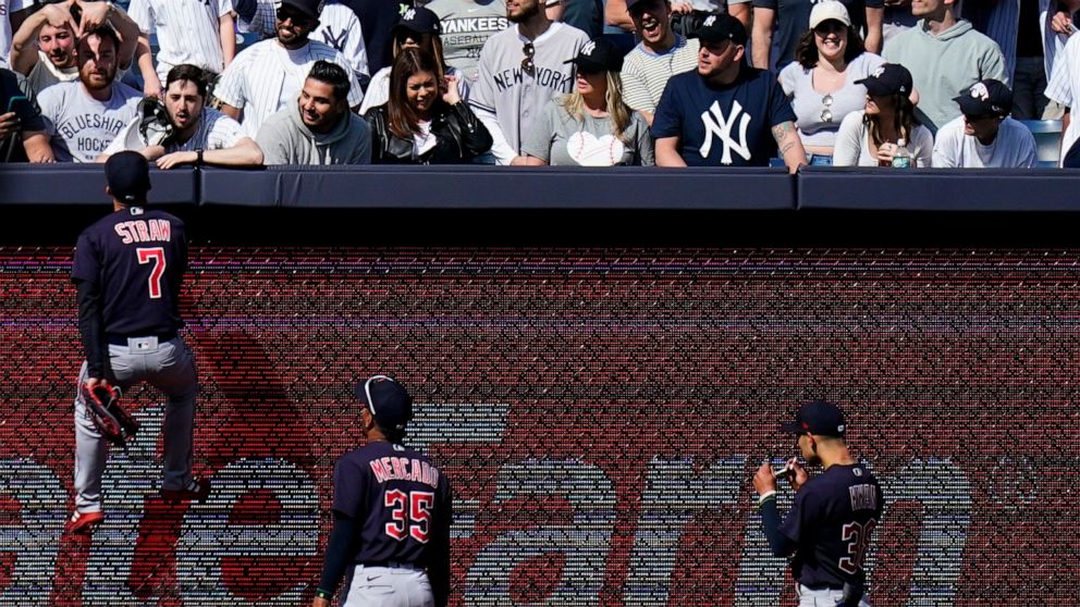Cleveland Guardians' Myles Straw (7) climbs the left field wall to talk with a fan during the ninth inning of a baseball game against the New York Yankees Saturday, April 23, 2022, in New York. The Yankees won 5-4. (AP Photo/Frank Franklin II)
