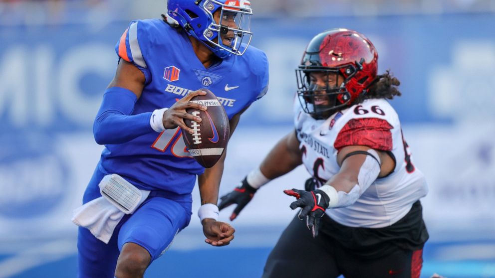 Boise State quarterback Taylen Green (10) is chased out of the pocket by San Diego State defensive lineman Jonah Tavai (66) during the first half of an NCAA college football game Friday, Sept. 30, 2022, in Boise, Idaho. (AP Photo/Steve Conner)