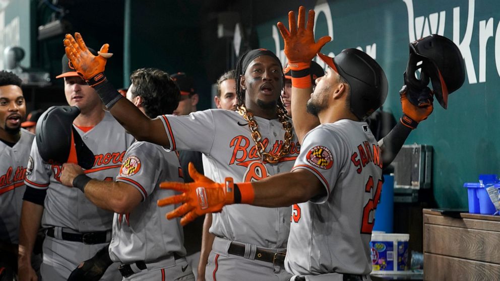 Baltimore Orioles shortstop Jorge Mateo, center, and Anthony Santander, right, celebrate in the dugout after Mateo hit a two-run home run in the ninth inning of a baseball game against the Texas Rangers, Tuesday, Aug. 2, 2022, in Arlington, Texas. Th