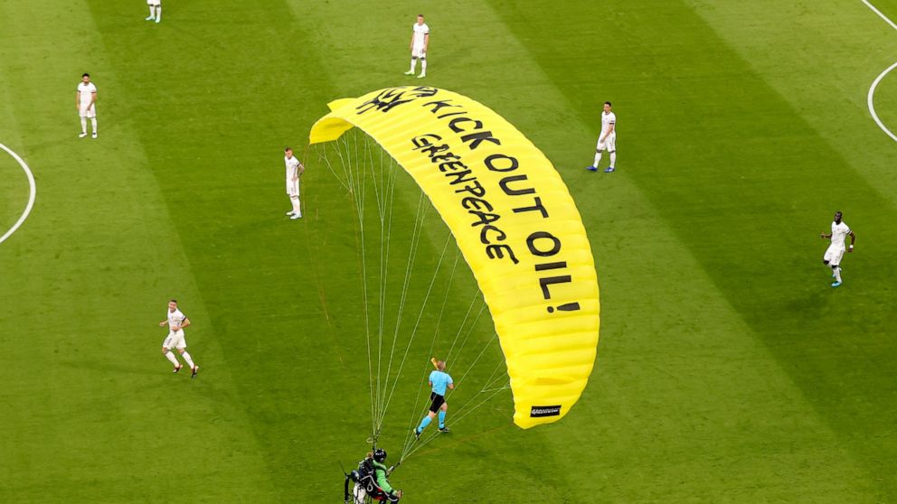 The German players look on as a Greenpeace paraglider lands in the stadium prior to the Euro 2020 soccer championship group F match between France and Germany at the Allianz Arena stadium in Munich, Tuesday, June 15, 2021. (AP Photo/ctivist Alexander