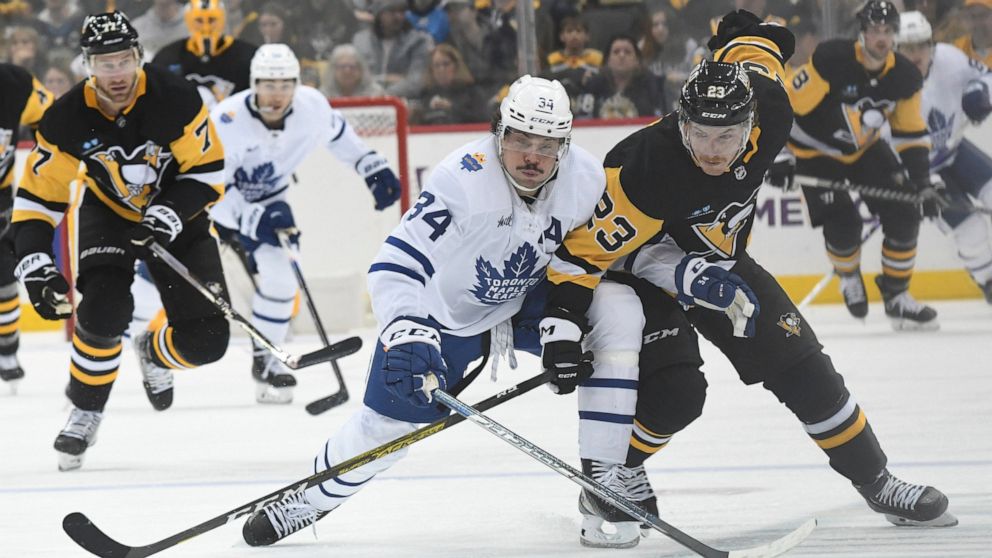 Pittsburgh Penguins left wing Brock McGinn (23) and Toronto Maple Leafs center Auston Matthews go for the puck during the second period of a hockey game, Saturday, Nov. 26, 2022, in Pittsburgh. (AP Photo/Philip G. Pavely)