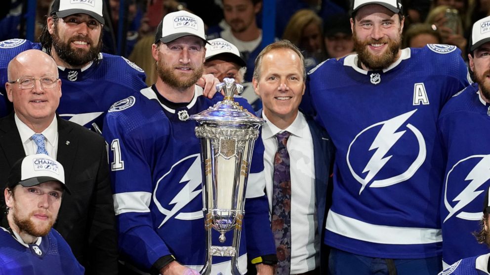Tampa Bay Lightning center Steven Stamkos (91), head coach Jon Cooper, and defenseman Victor Hedman (77) pose with the Prince of Wales Trophy after the team defeated the New York Rangers during Game 6 of the NHL hockey Stanley Cup playoffs Eastern Co