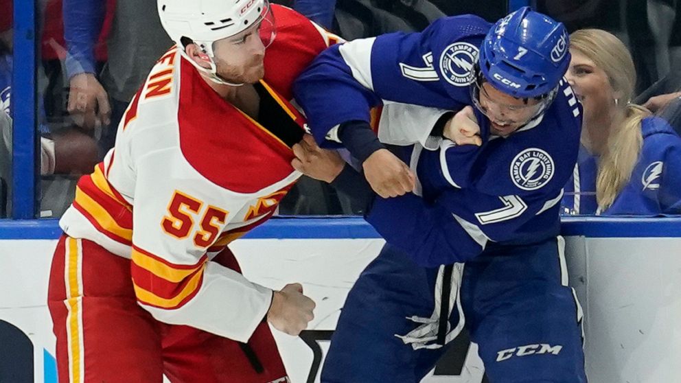 Calgary Flames defenseman Noah Hanifin (55) and Tampa Bay Lightning right wing Mathieu Joseph (7) fight during the first period of an NHL hockey game Thursday, Jan. 6, 2022, in Tampa, Fla. (AP Photo/Chris O'Meara)