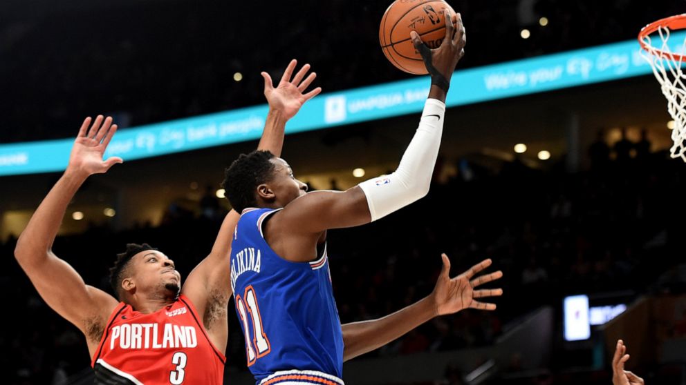 New York Knicks guard Frank Ntilikina, left, drives to the basket on Portland Trail Blazers guard CJ McCollum, right, during the first half of an NBA basketball game in Portland, Ore., Tuesday, Dec. 10, 2019. (AP Photo/Steve Dykes)
